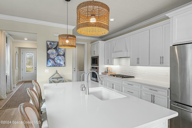 kitchen with appliances with stainless steel finishes, custom range hood, sink, white cabinets, and light hardwood / wood-style floors