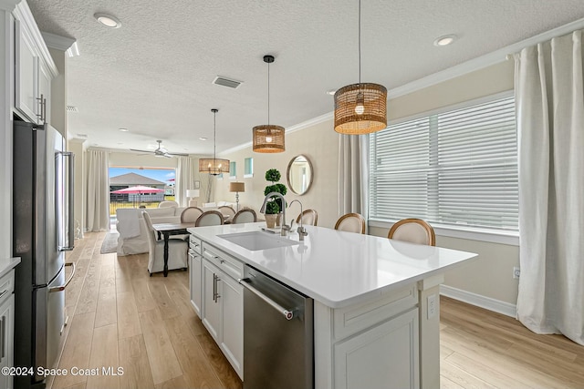 kitchen with white cabinetry, sink, an island with sink, light hardwood / wood-style floors, and appliances with stainless steel finishes