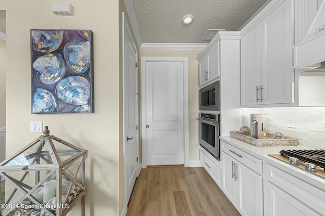 kitchen with white cabinets, stainless steel appliances, a textured ceiling, and light wood-type flooring