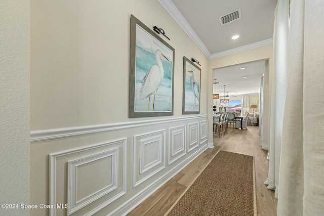 hallway featuring an inviting chandelier, light hardwood / wood-style flooring, and ornamental molding