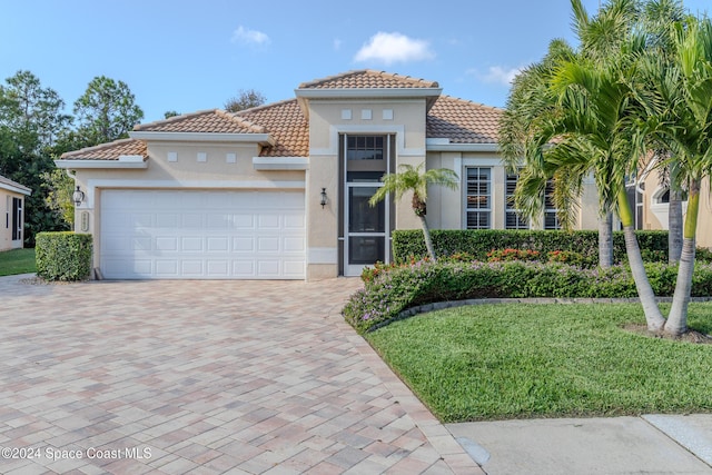 mediterranean / spanish-style home with a garage and a front lawn