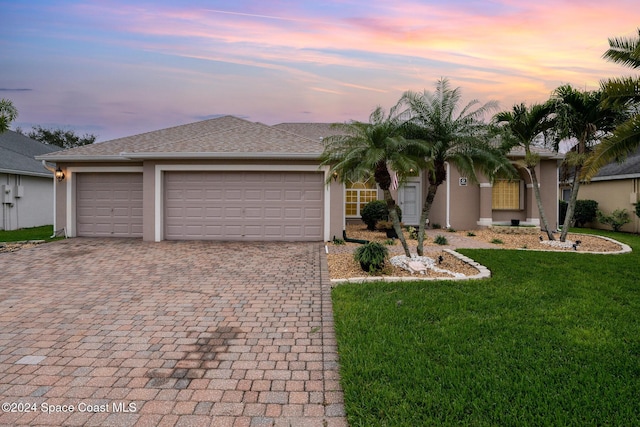 single story home featuring a garage and a lawn