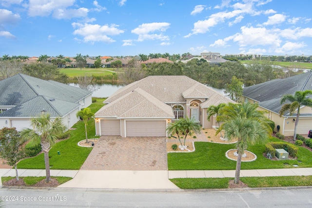 view of front of house featuring a front yard, a garage, and a water view