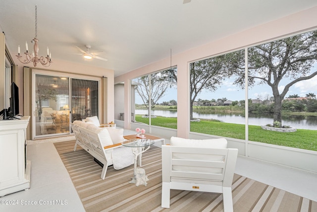 sunroom with ceiling fan with notable chandelier and a water view