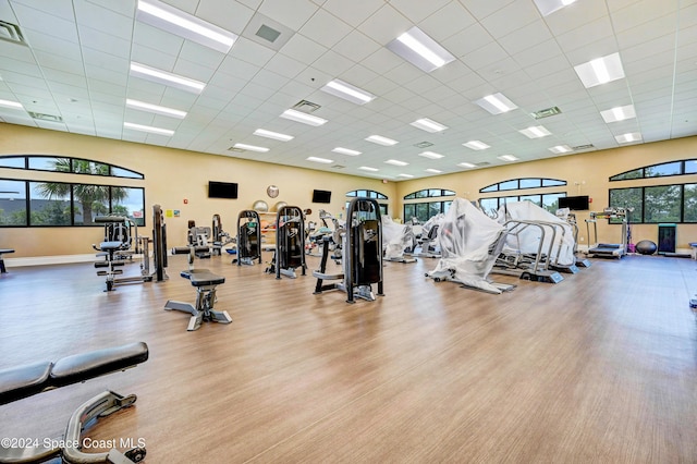 workout area with a paneled ceiling and light hardwood / wood-style floors