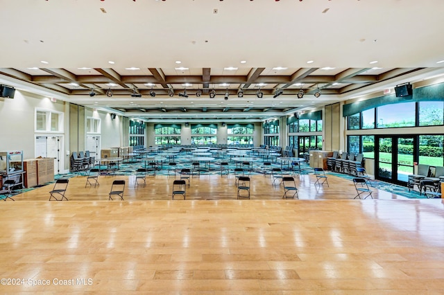 workout area with light wood-type flooring, track lighting, and coffered ceiling