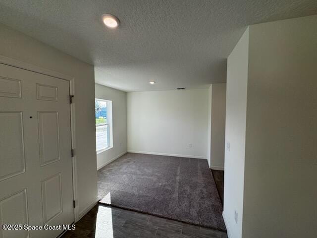 entryway with dark colored carpet and a textured ceiling