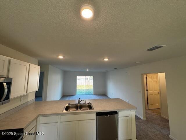 kitchen featuring sink, kitchen peninsula, carpet floors, white cabinets, and appliances with stainless steel finishes