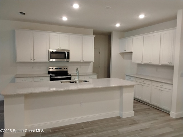 kitchen with sink, white cabinetry, a center island with sink, appliances with stainless steel finishes, and light hardwood / wood-style floors