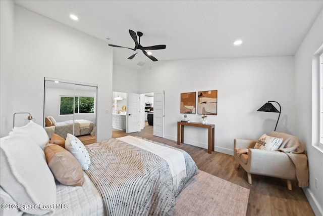 bedroom featuring wood-type flooring, ensuite bath, ceiling fan, and lofted ceiling