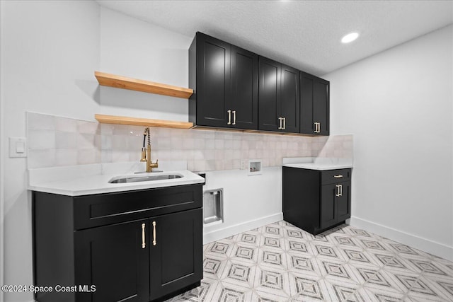 laundry room featuring hookup for a washing machine, sink, cabinets, and a textured ceiling