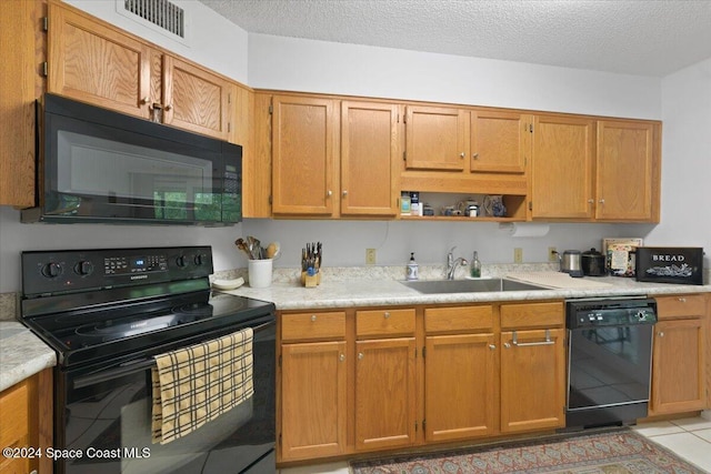 kitchen featuring black appliances, light tile patterned flooring, sink, and a textured ceiling