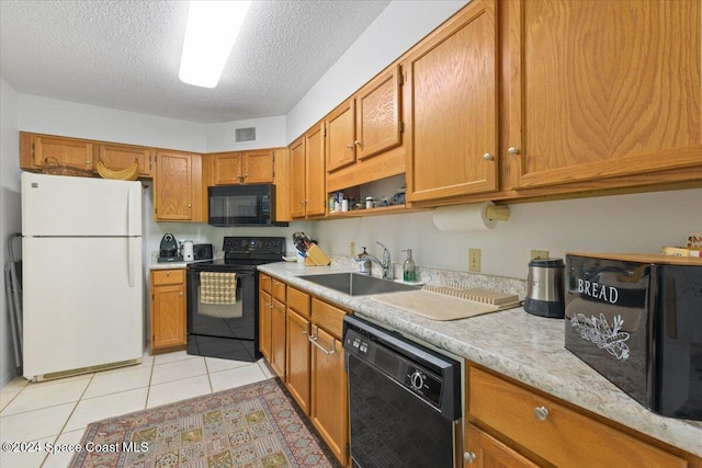 kitchen featuring sink, light tile patterned floors, black appliances, and a textured ceiling
