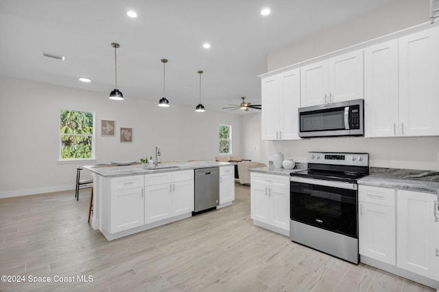 kitchen with pendant lighting, plenty of natural light, white cabinetry, and stainless steel appliances