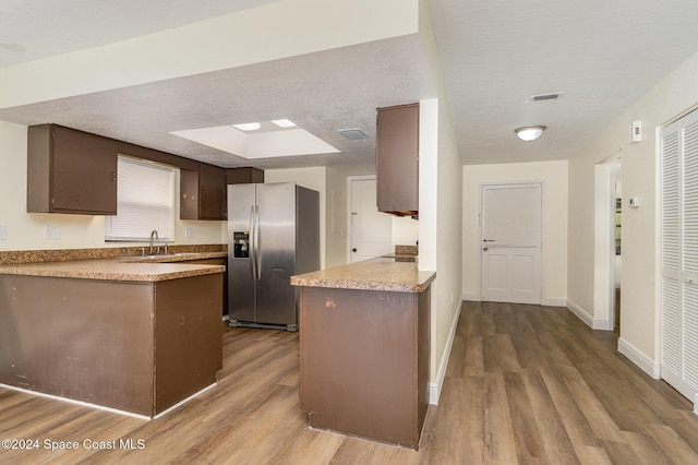 kitchen with stainless steel refrigerator with ice dispenser, dark brown cabinets, a textured ceiling, sink, and wood-type flooring