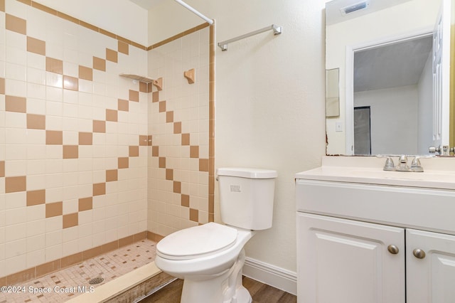 bathroom with tiled shower, vanity, wood-type flooring, and toilet