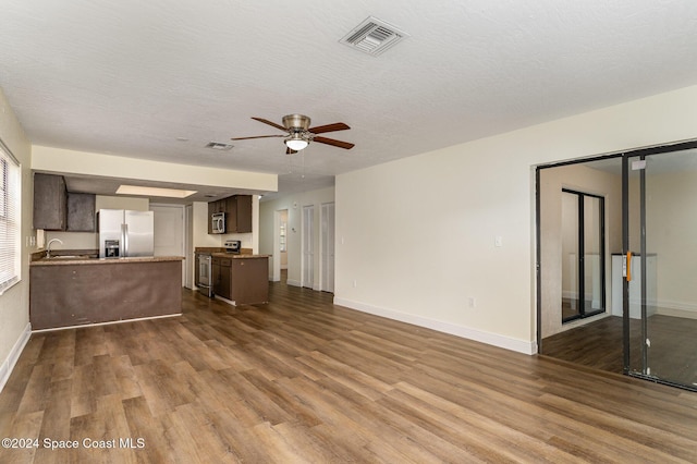 unfurnished living room with ceiling fan, sink, wood-type flooring, and a textured ceiling