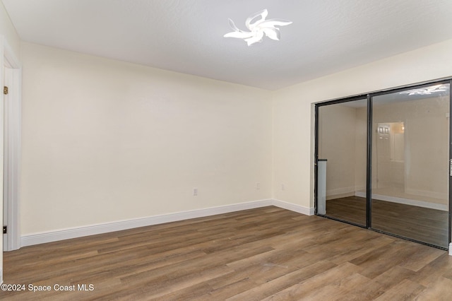 unfurnished bedroom with wood-type flooring, an inviting chandelier, and a closet