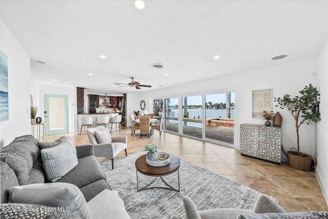 living room featuring ceiling fan and a water view