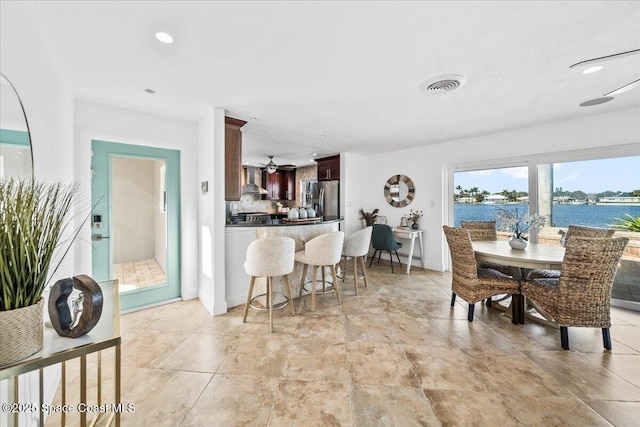 dining area featuring ceiling fan and a water view