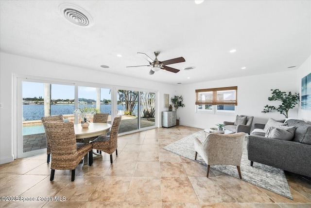 dining room with ceiling fan and a water view