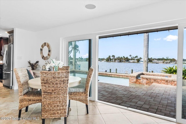 dining room featuring light tile patterned flooring and a water view