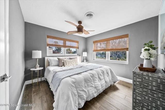 bedroom featuring ceiling fan, multiple windows, and hardwood / wood-style flooring