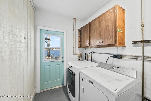 washroom with cabinets, washer and clothes dryer, and a water view