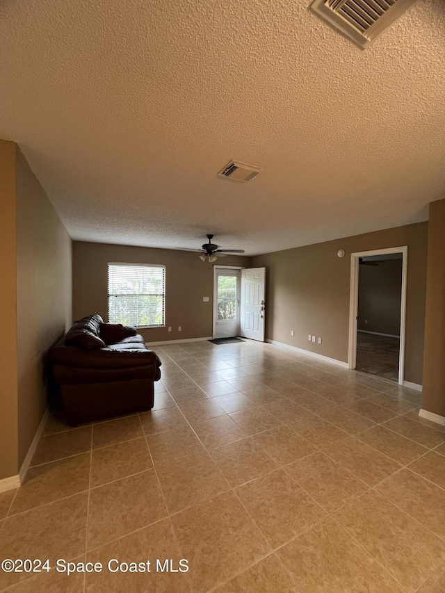 living room featuring tile patterned floors, ceiling fan, and a textured ceiling