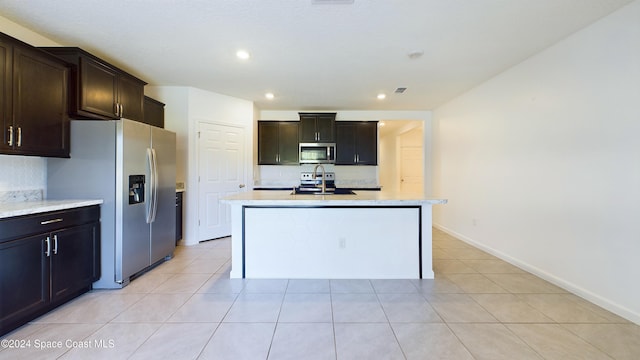 kitchen featuring dark brown cabinetry, sink, a center island with sink, light tile patterned floors, and appliances with stainless steel finishes