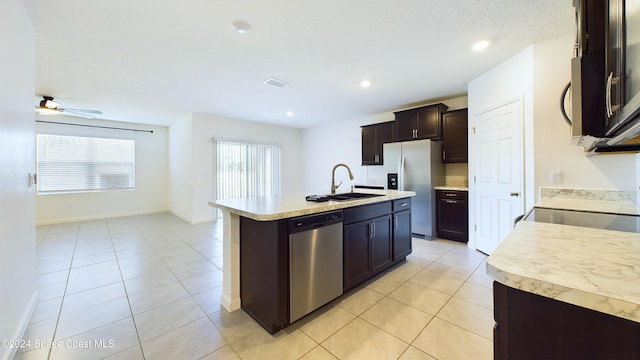 kitchen featuring appliances with stainless steel finishes, ceiling fan, sink, light tile patterned floors, and a center island with sink