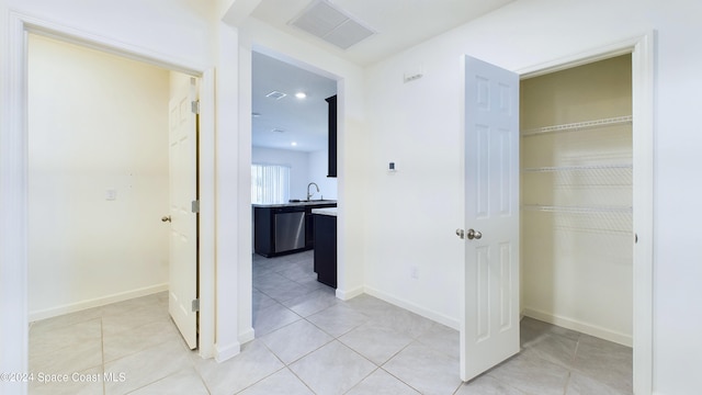 corridor featuring light tile patterned floors and sink