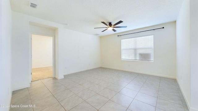 tiled empty room featuring a textured ceiling and ceiling fan