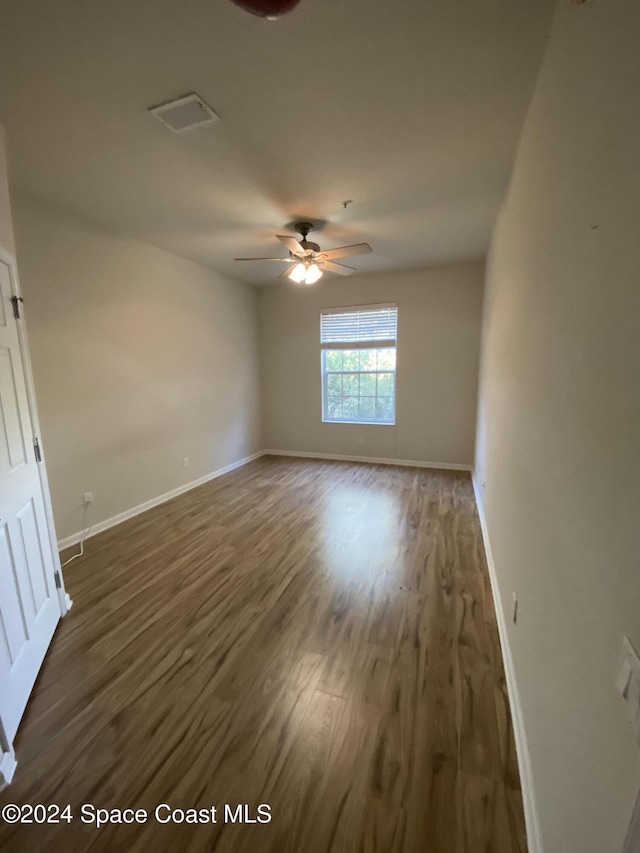 empty room with ceiling fan and dark wood-type flooring