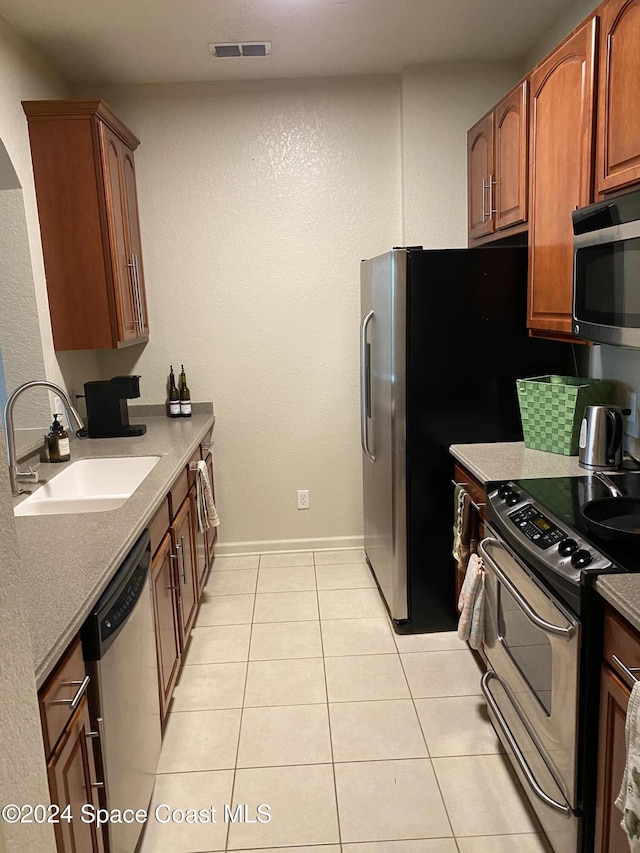 kitchen with light tile patterned flooring, stainless steel appliances, and sink