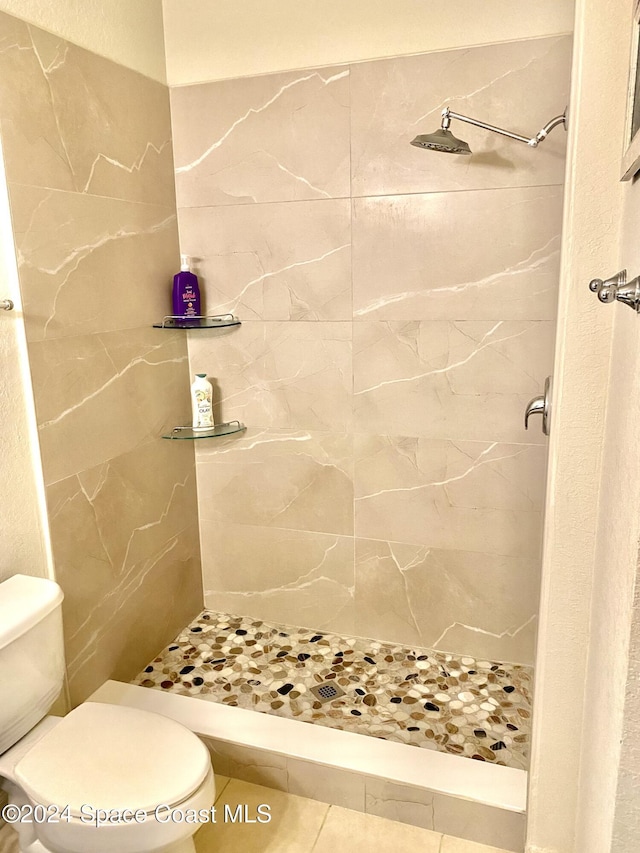 bathroom featuring toilet, tile patterned flooring, and tiled shower