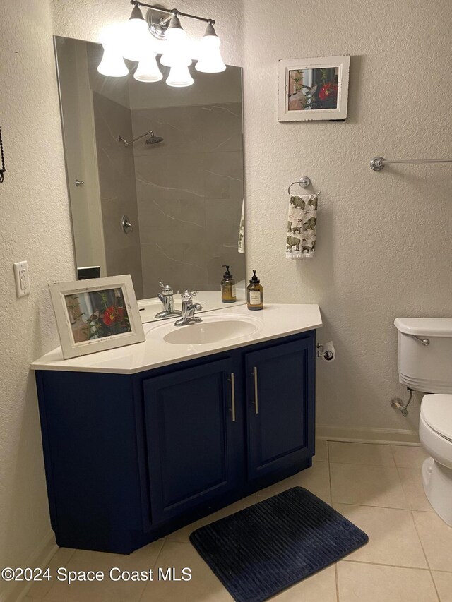 bathroom featuring toilet, vanity, tiled shower, and tile patterned floors