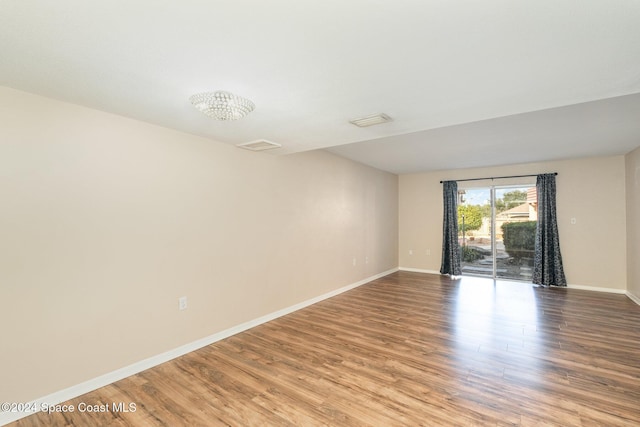 empty room with a chandelier and hardwood / wood-style floors