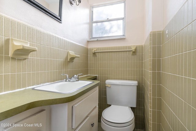 bathroom featuring vanity, toilet, and tile walls