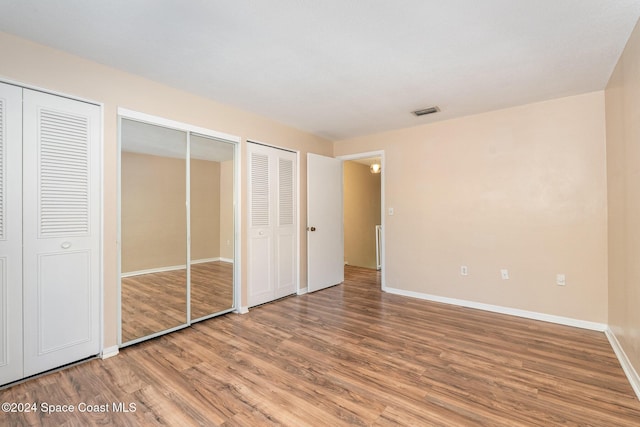 unfurnished bedroom featuring two closets and hardwood / wood-style flooring