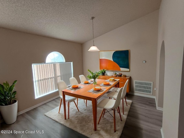 dining room with a textured ceiling, hardwood / wood-style floors, and lofted ceiling