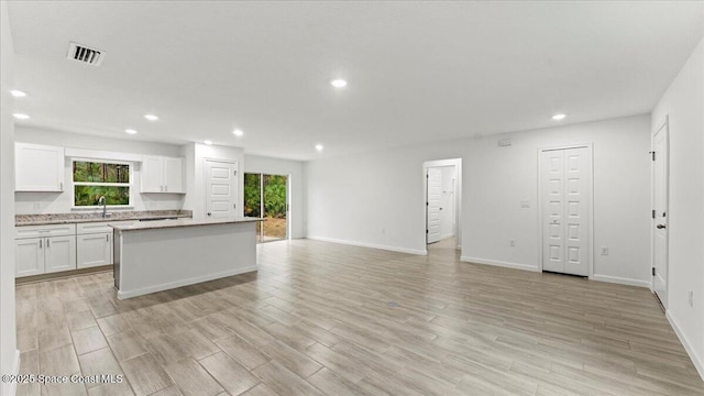 kitchen featuring a healthy amount of sunlight, light hardwood / wood-style floors, white cabinets, and a kitchen island