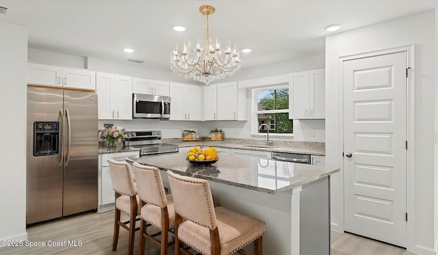 kitchen with stainless steel appliances, a center island, sink, and white cabinets