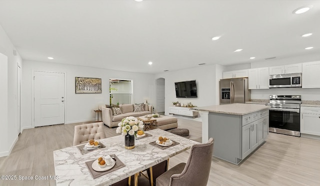 kitchen with gray cabinetry, white cabinets, a center island, stainless steel appliances, and light hardwood / wood-style flooring