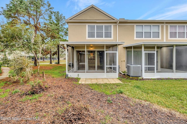 rear view of property featuring a sunroom, central AC, and a yard