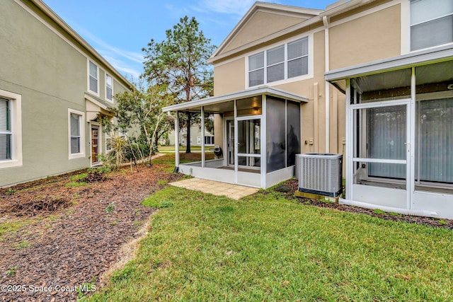 back of house featuring a sunroom, a lawn, and central AC