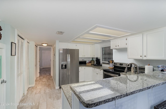 kitchen featuring white cabinets, appliances with stainless steel finishes, light hardwood / wood-style floors, and kitchen peninsula