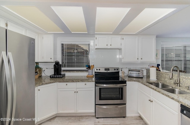 kitchen featuring white cabinetry, sink, stainless steel appliances, and light stone counters