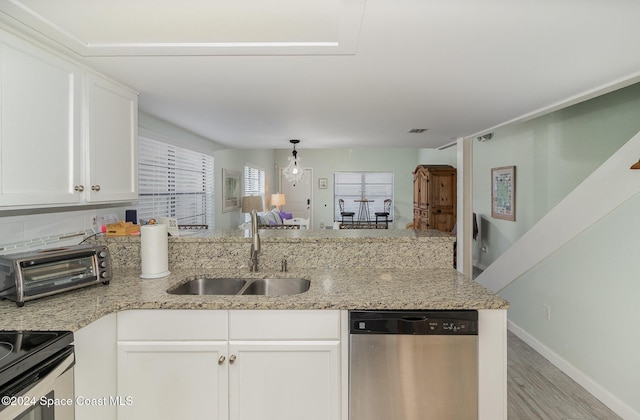 kitchen with white cabinets, sink, light hardwood / wood-style flooring, stainless steel dishwasher, and kitchen peninsula