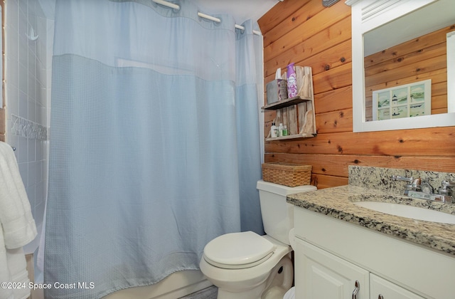 bathroom with vanity, toilet, and wood walls